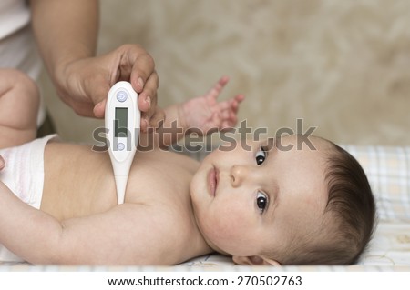 mother measures the temperature of a baby child kid