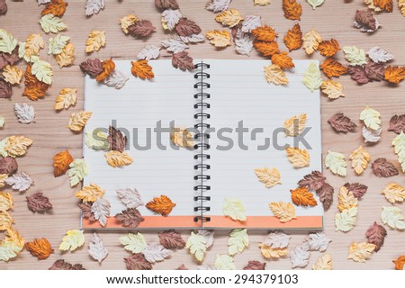 Spiral notebook with maple leaves on wood background in autumn