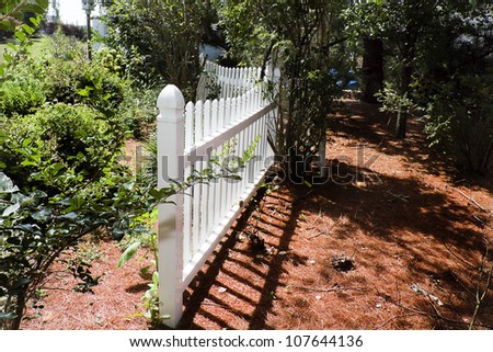 Closeup of white picket fence in garden