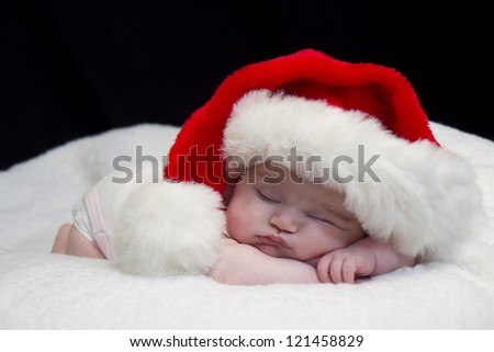 Baby girl wearing red santa hat while sleeping and peeking at times