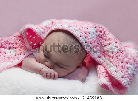 Small baby sleeping with hand made crochet blanket laying across her head