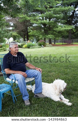 Senior Citizen enjoying the comforts of his home in backyard with his dog sitting next to him
