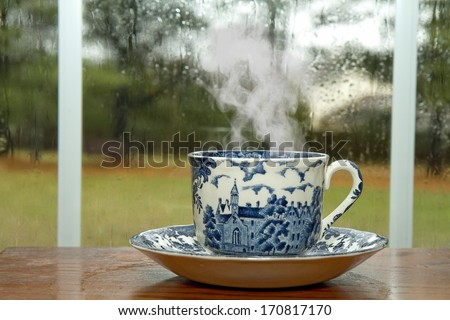 Antique Cup and Saucer with hot coffee by window on rainy day