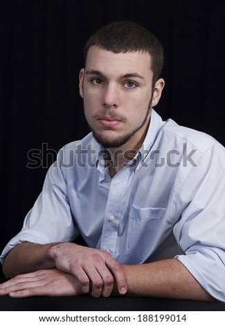 Senior graduate photo of young male with facial hair wearing blue shirt