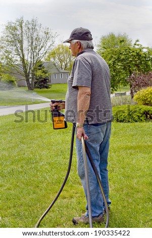 Senior male spraying his lawn with weed killer