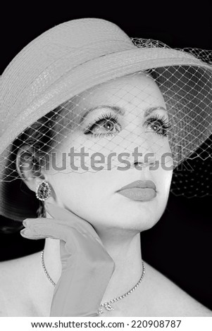 Dreamy retro/vintage portrait of woman wearing retro hat with netting coming down her face.  Black and White