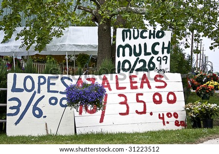 Roadside produce stand with huge home-made signs set outside to entice customers.