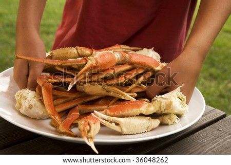 Boy gathering up crab legs off from large serving plate