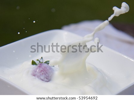 Strawberry dropped into bowl of milk making a splash