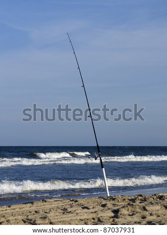 Surf fishing rod placed in sand with spike by ocean
