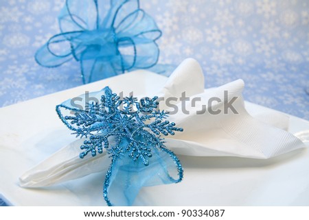 Sparkly blue snowflake napkin holder resting on white plate with soft blue/white snowflake backdrop ready for the holidays...
