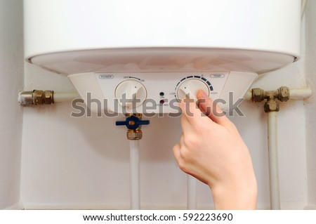 Hands young women set the temperature of the water in the electric boiler. Close up of female hands turning the handle of an electric boiler.