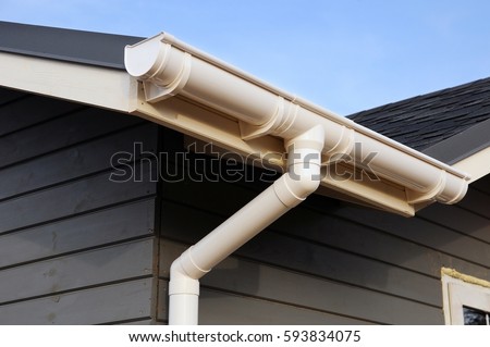 Frame house Rain gutter system. White gutter on the roof top of house.