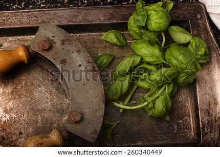 A bunch of fresh basil leaves on a vintage metal tray with a chopper