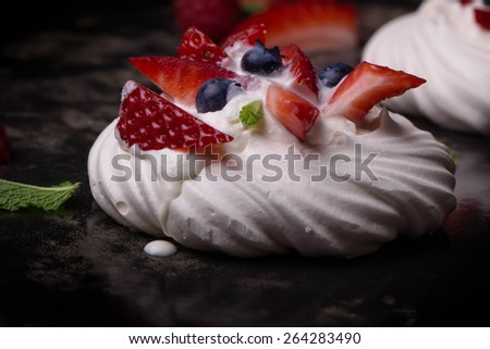 Pavlova berry cake with blueberries, strawberries and raspberries and whipped cream on the blue ceramic tray
