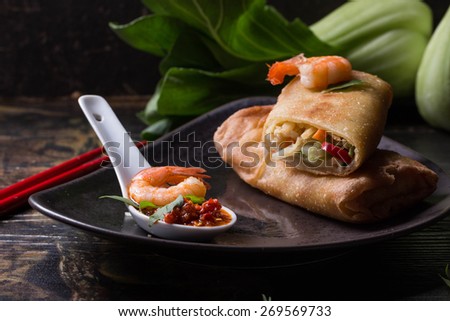 Fried spring rolls with  shrimps, bok choi, chili pepper and hot sauce on a vintage ceramic plate.