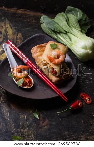 Fried spring rolls with  shrimps, bok choi, chili pepper and hot sauce on a vintage ceramic plate.
