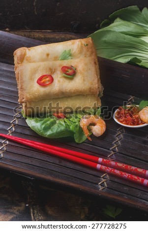 Fried spring rolls with  shrimps, bok choi, chili pepper, hot sauce on a vintage bamboo tray
