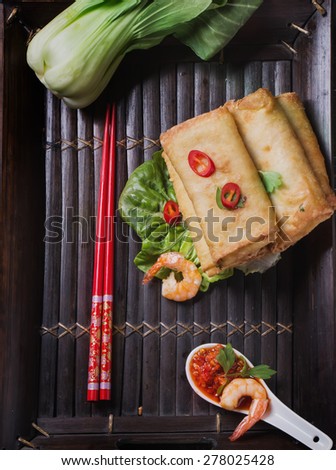 Fried spring rolls with  shrimps, bok choi, chili pepper and hot sauce on a vintage bamboo tray