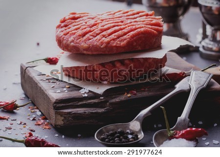 Raw Ground beef meat Burger steak cutlets with seasoning on vintage wooden boards, black background