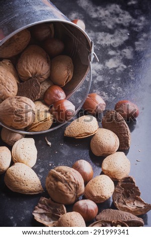 Selection of various nuts: almonds, Brazilian, walnuts in the tiny vintage bucket, black background