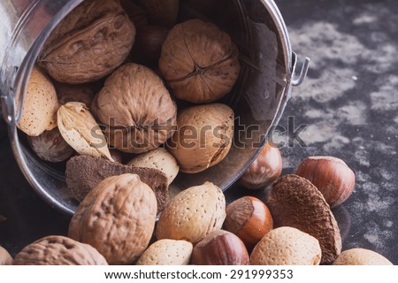 Selection of various nuts: almonds, Brazilian, walnuts in the tiny vintage bucket, black background