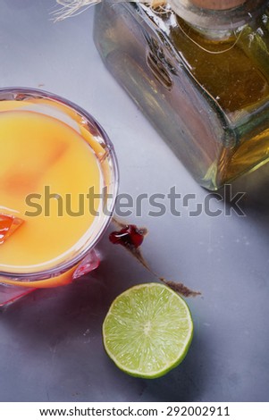 Tequila Sunrise served in a highball glass with ice, grenadine and lime