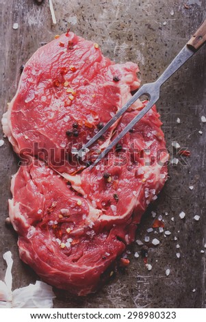 Raw fresh meat Ribeye Steak, with seasoning and meat fork on vintage metal tray