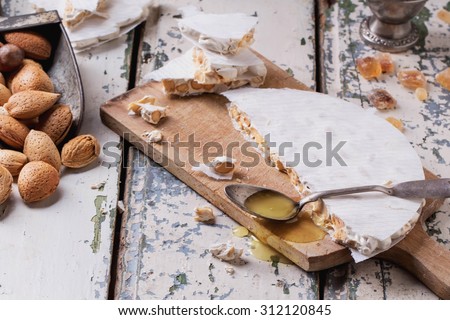 Traditional Spanish Christmas candy turron served on rustic wooden board with honey, almonds and sugar candies on rustic background