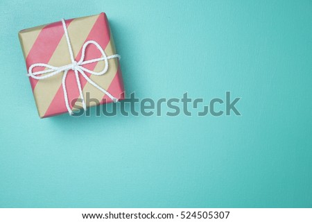 Craft paper wrapped present box craft rope bow ribbon on blue background, top view
