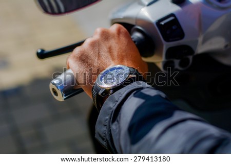 Man wearing a watch. Man is on a motorcycle, ready to go.