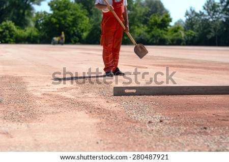 Worker with a shovel. Photo was taken on a construction site, while worker was standing with his shovel in front of a metal bar for leveling the ground