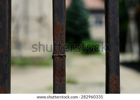 Black iron fence close up. The fence is very old and rusted. Photo was taken about noon, on a nice sunny day in Szeged, Hungary.
