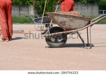 Iron cart full of sand. Construction workers are in the background with shovels. Photo was taken on a construction site near football stadium Spartak Subotica, Serbia.