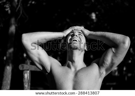 Man photographed in street workout session. Holding hands on the head and smiling. Photo was taken in early morning, around 6am in city park Dudova forest. Black and white photo.