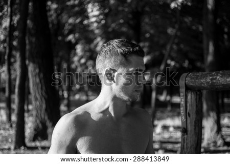 Man photographed in street workout session. Looking to start another exercise. Photo was taken in early morning, around 6am in city park Dudova forest. Black and white photo.
