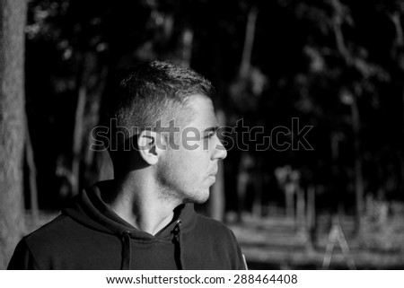 Man photographed in street workout session. He is wearing black sweat shirt. Photo was taken in early morning, around 6am in city park Dudova forest. Black and white photo.
