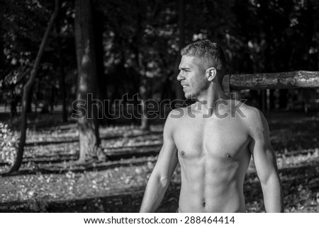 Man photographed in street workout session.Finished one of his exercises and looking towards the sun.Photo was taken in early morning, around 6am in city park Dudova forest. Black and white photo.