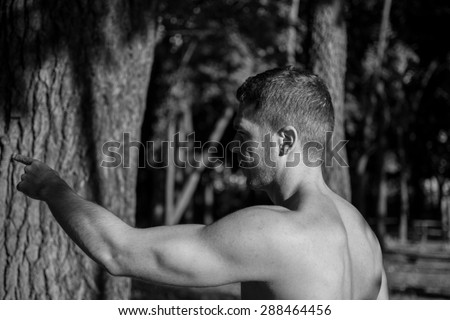 Man photographed in street workout session. Just finished one of his exercises and pointing whats next. Photo was taken in early morning, around 6am in city park Dudova forest. Black and white photo.