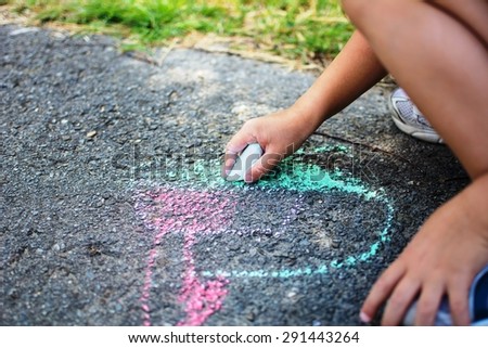 Children draw in the park with chalks of various colors. Selective focus on hand.