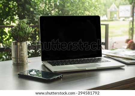 Laptop computer, phone ,books and plant on the table  in the garden, small depth of field.