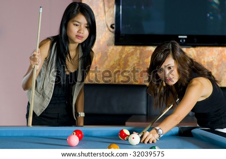 pretty asian women playing pool. focus on the one who is playing.