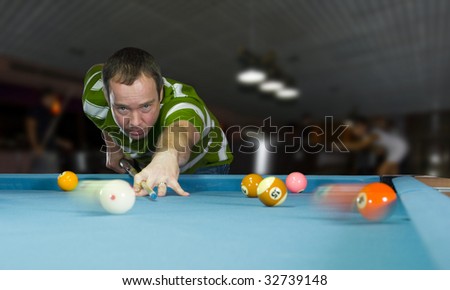 caucasian man playing an eight ball pool game in a pool bar