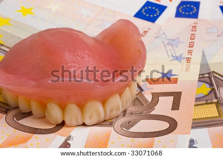 false teeth prosthetic on euro bills with focus on the front teeth