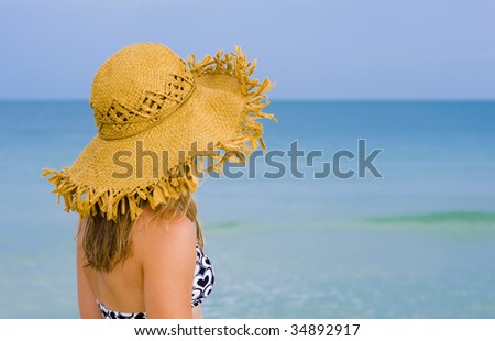 young blond woman with hat watching the sea