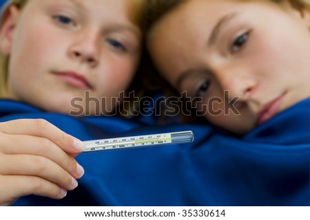 two girls sick in bed, having over 39?C /102?F fever. focus on thermometer with a shallow dept of field.