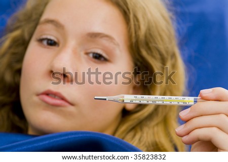girl sick in bed, having over 39?C /102?F fever. with a shallow depth of field - focus on thermometer.
