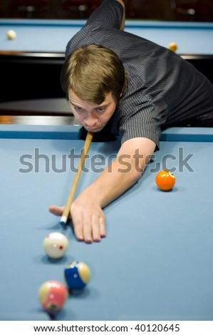 8 ball pool game: caucasian taking a shoot. focus on his face with a shallow depth of field