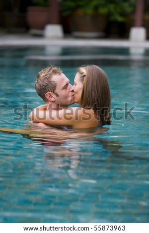 man and woman kissing each other in a swimming pool