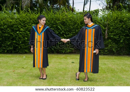two proud and happy asian students posing on their graduation day